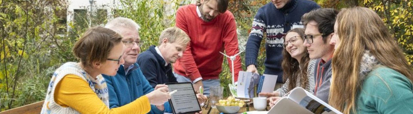 Gruppe draußen am Tisch plant und diskutiert Klimaschutz